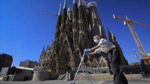 Un hombre mayor pasea en patinete ante una Sagrada Família desierta.