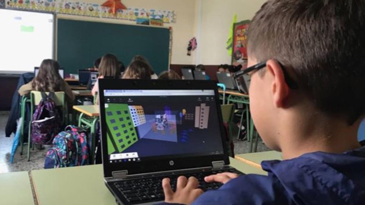 Un alumno trabajando en clase con un ordenador portátil.