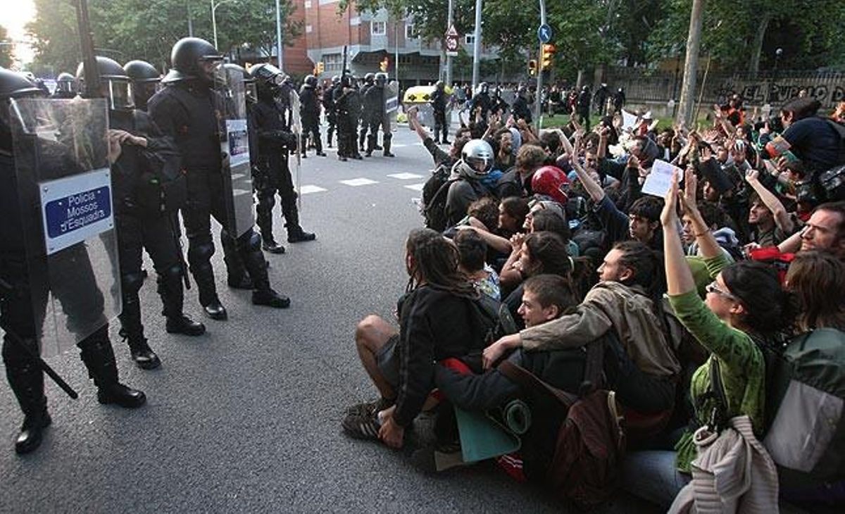 Un grup de manifestants asseguts davant un cordó d’agents antiavalots.
