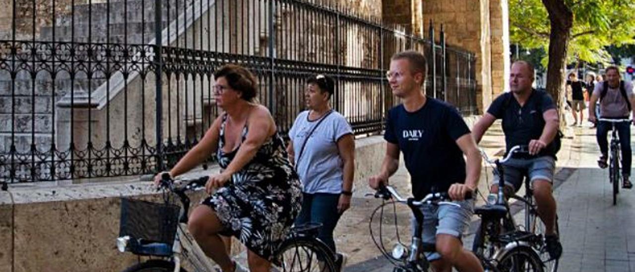 Turistas en bicicleta junto a las Torres de Serranos. | GERMÁN CABALLERO