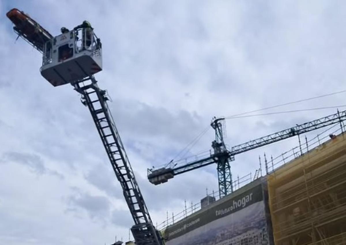 Los bomberos bajando al herido en camilla con el camión grúa.