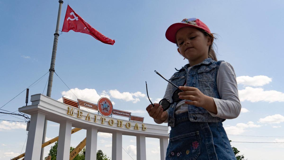 Una niña posa frente a un arco coronado por una bandera soviética en Melitopol, una ciudad del sureste de Ucrania ocupada por las tropas rusas.