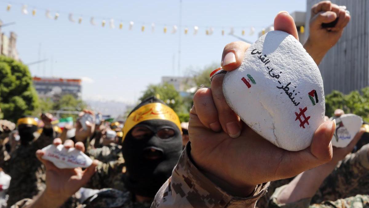 Un miembro de las fuerzas paramilitares Basij sostiene una piedra con una frase que reza en árabe 'Pronto estaremos en Quds' durante una concentración.