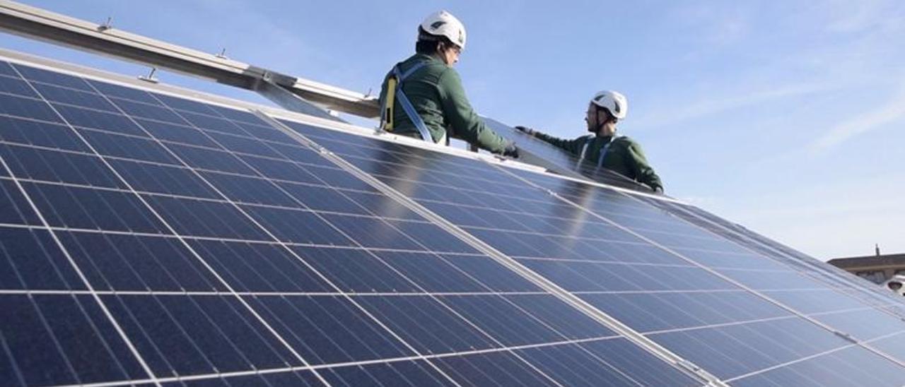 Dos operarios instalan
placas solares en la azotea
den una comunidad.  ep