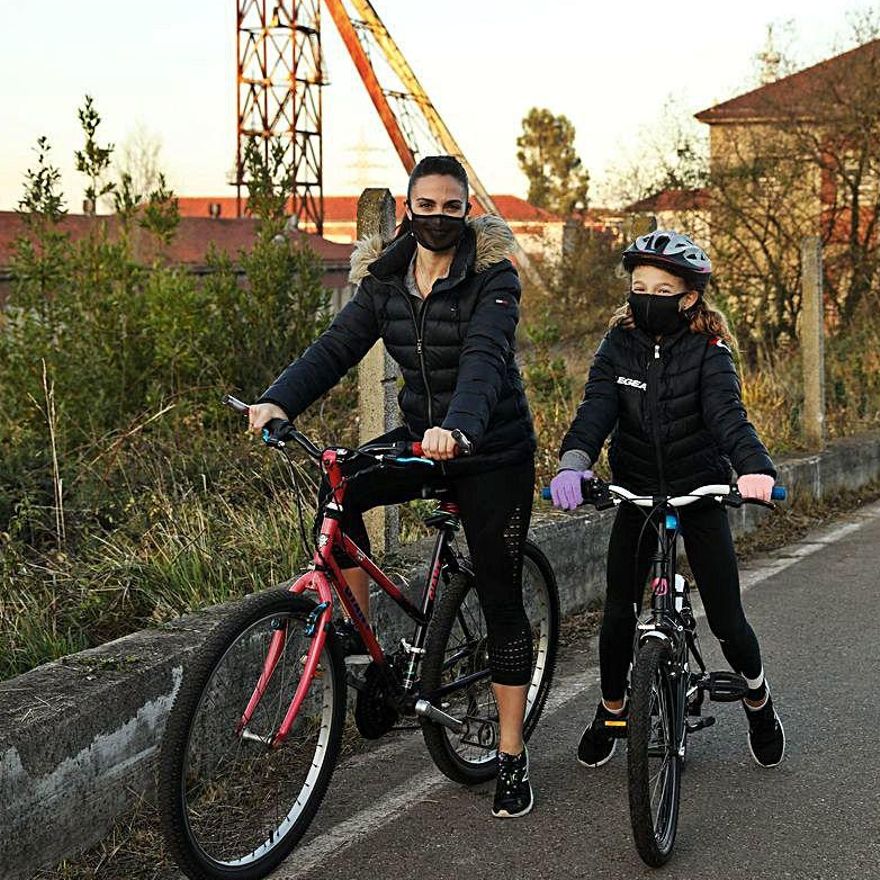 Eva Meana y la pequeña Gabriela Pool, en sus bicicletas, junto a la mina de La Camocha. | | JUAN PLAZA