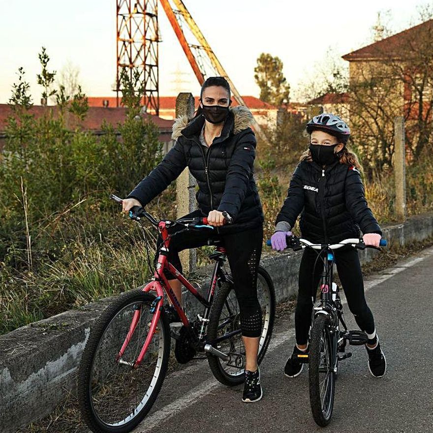 Eva Meana y la pequeña Gabriela Pool, en sus bicicletas, junto a la mina de La Camocha. | |  JUAN PLAZA