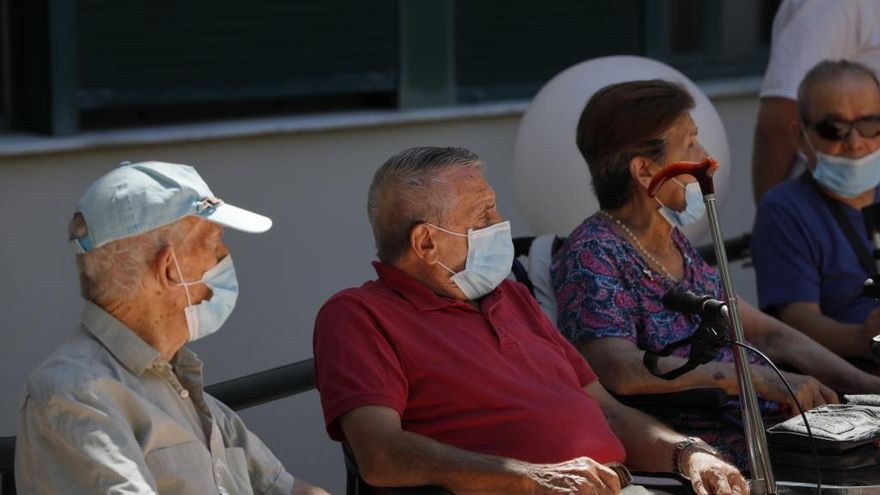 Varios ancianos descansan en un banco con su correspondiente mascarilla.