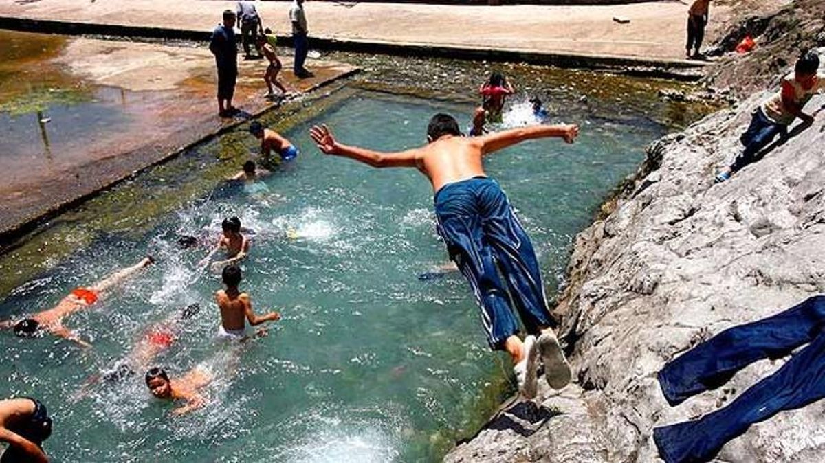 Un nen salta a una piscina a la localitat iraniana de Shahre Ray. Desenes de nens juguen en aquest embassament per burlar temperatures, que superen els 43º.