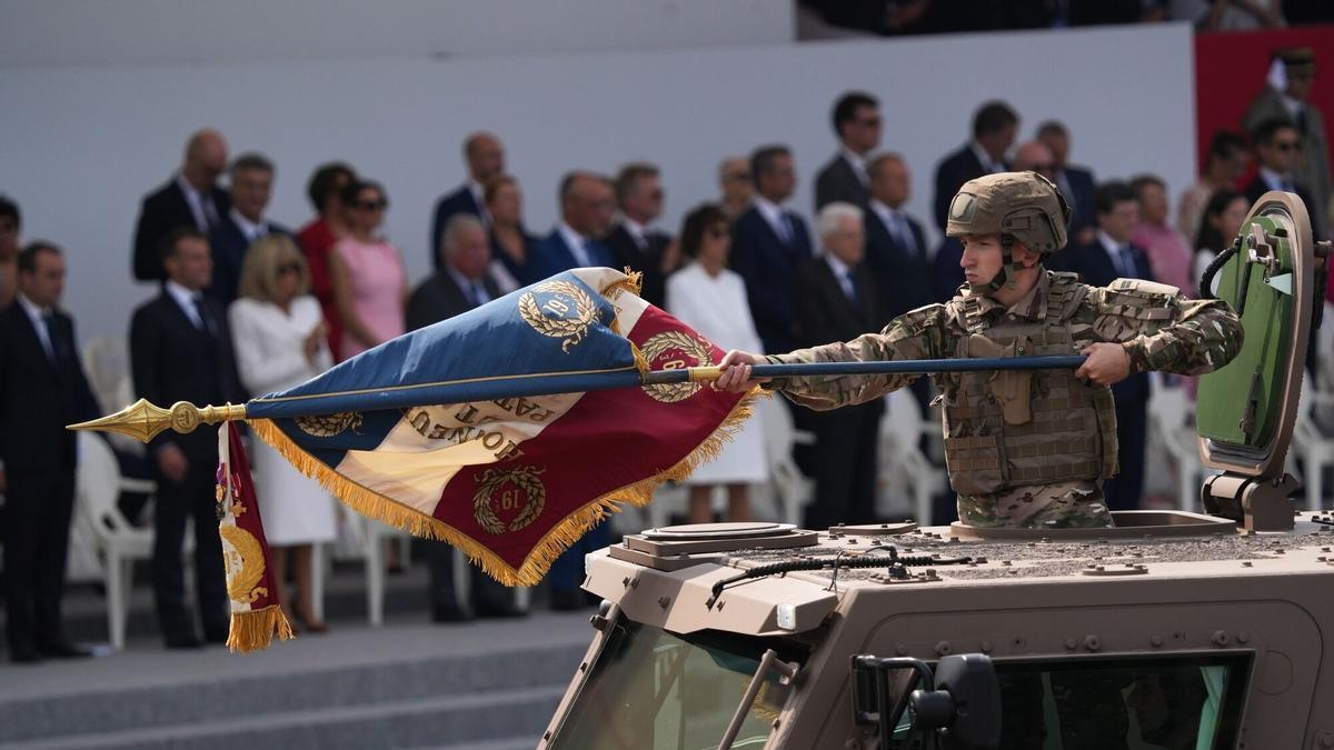 Un soldado porta una bandera militar francesa a bordo de un vehículo durante el desfile del 14 de julio de 2026.