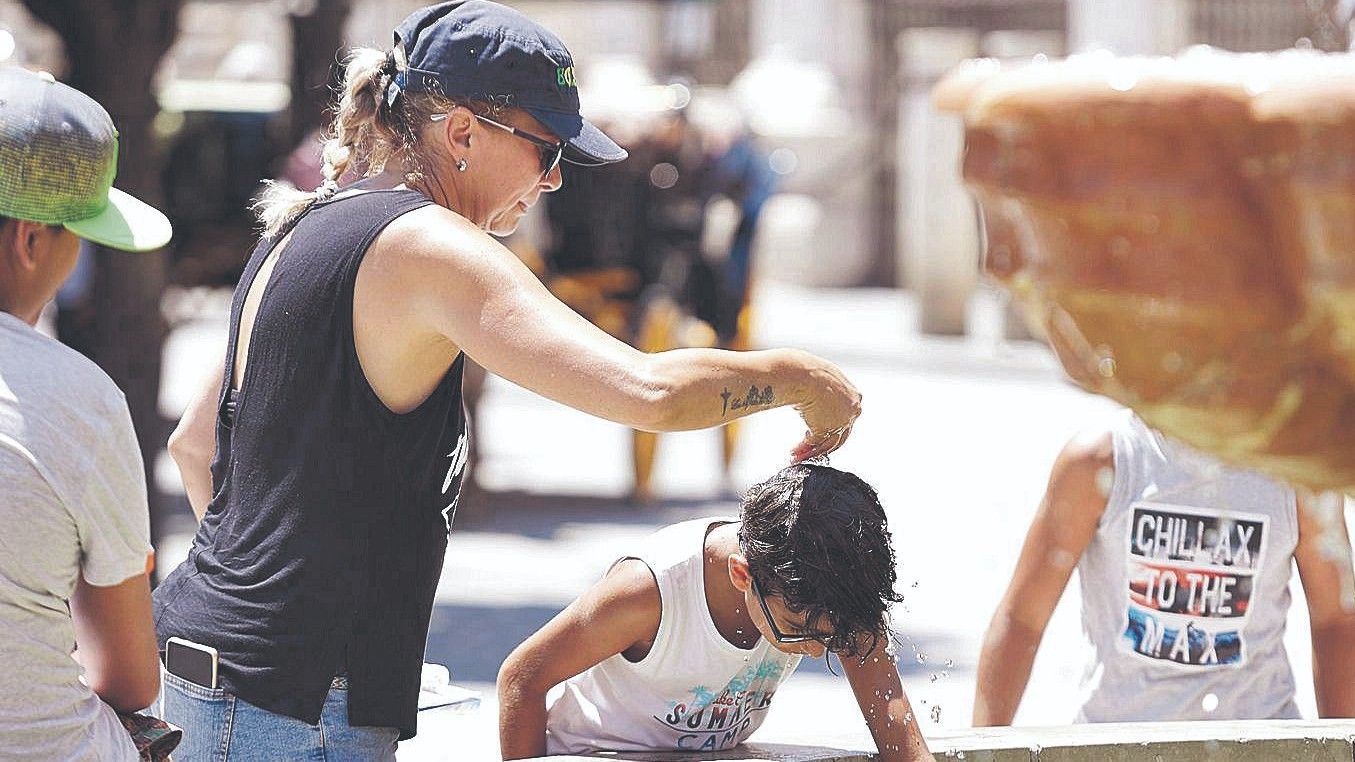Una mujer echa agua por la cabeza a un niño en Sevilla, el pasado 7 de julio