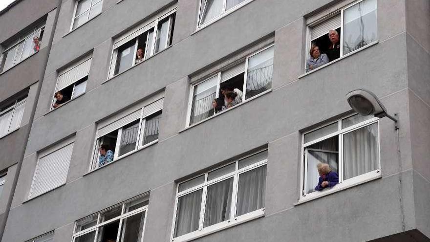 Vecinos de una calle de A Coruña asomados a las ventanas durante el confinamiento.