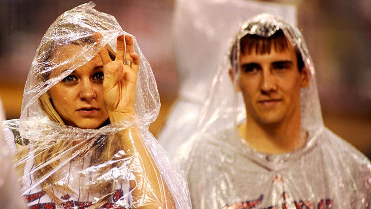 Una parella de seguidors de l’equip de beisbol Mellizos de Minnesota observa el seu equip enmig de la pluja.
