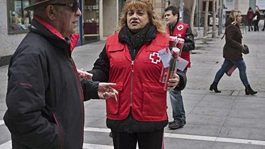 Una voluntaria ofrece rosas en la calle Santa Clara.