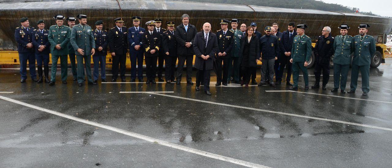 Las autoridades y fuerzas de seguridad del Estado junto al narcosubmarino una vez reflotado en el puerto de Aldán.