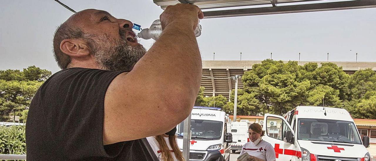 Una persona sin hogar se hidrata con una de las botellas de agua que reparte Cruz Roja.