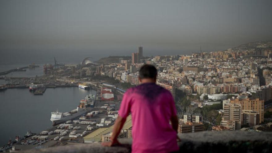 Un hombre observa la calima sobre Santa Cruz de Tenerife.