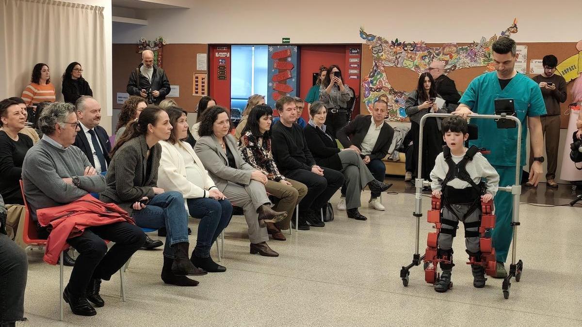El pequeño Darío da unos pasos asistidos con el exoesqueleto, con la ayuda del fisioterapeuta Santiago Carral, este miércoles, en las instalaciones de Aspace Coruña.