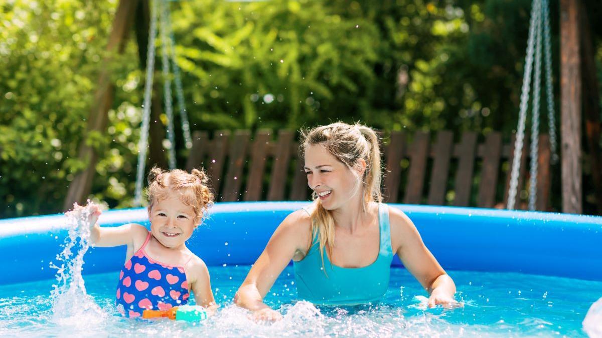 Una mujer juega con su hija en una piscina hinchable.