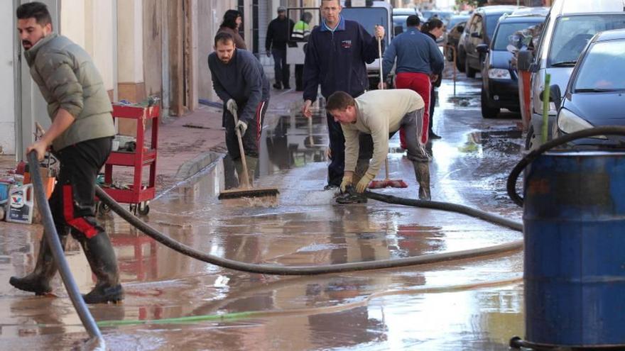 Afectados por las inundaciones quitan el agua y barro de las calles.