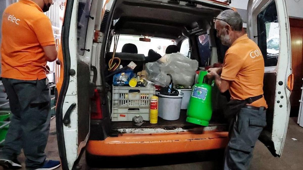 Dos trabajadores preparan el equipo necesario para su labor.