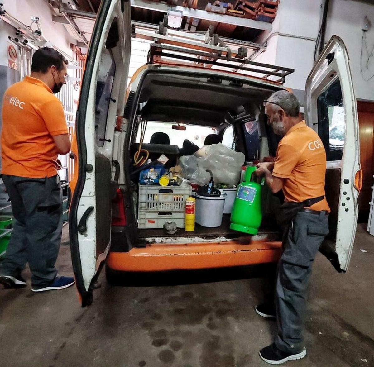 Dos trabajadores preparan el equipo necesario para su labor.