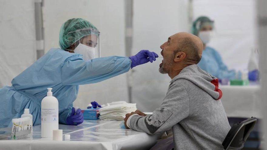 Una sanitaria hace un frotis bucal a un paciente durante la toma de muestras para realizar una PCR.