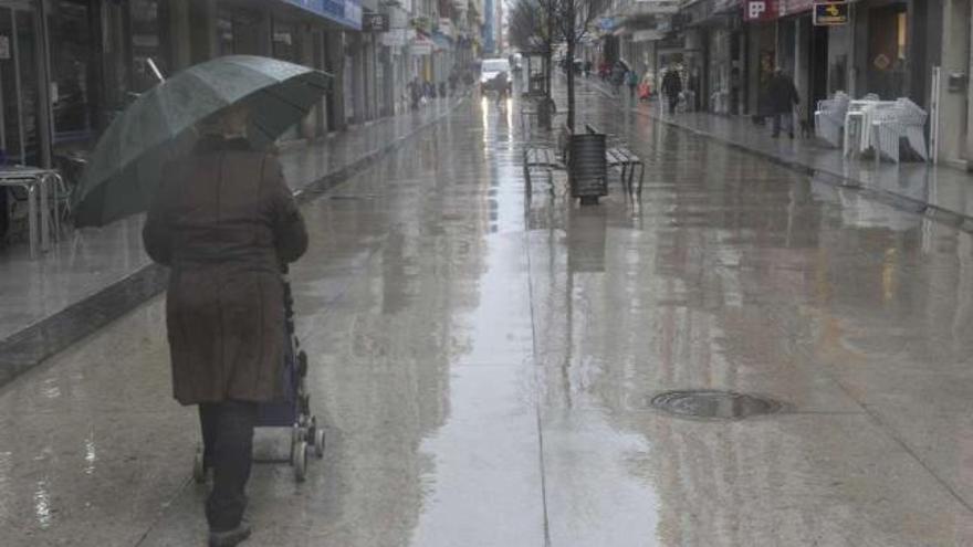 Una mujer se protege de la lluvia en una calle de A Coruña. / víctor echave