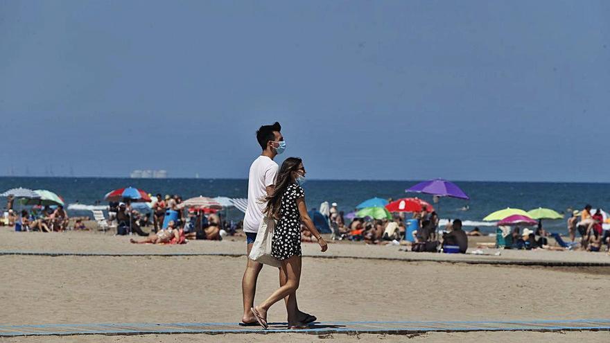 Una pareja accede a la playa de la Malva-rosa en València el primer fin de semana de uso obligatorio de la mascarilla.