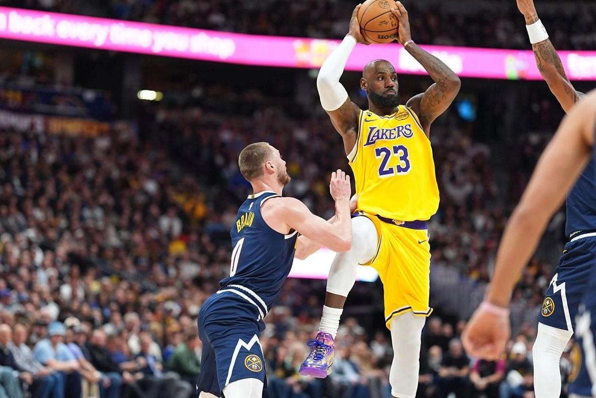 El alero de Los Angeles Lakers, LeBron James (derecha), pasa el balón mientras el base de los Denver Nuggets, Christian Braun, defiende.