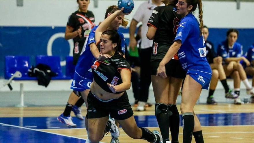 Una defensa del Ansa Oviedo trata de impedir un lanzamiento de la jugadora del Balonmano Gijón Lucía.