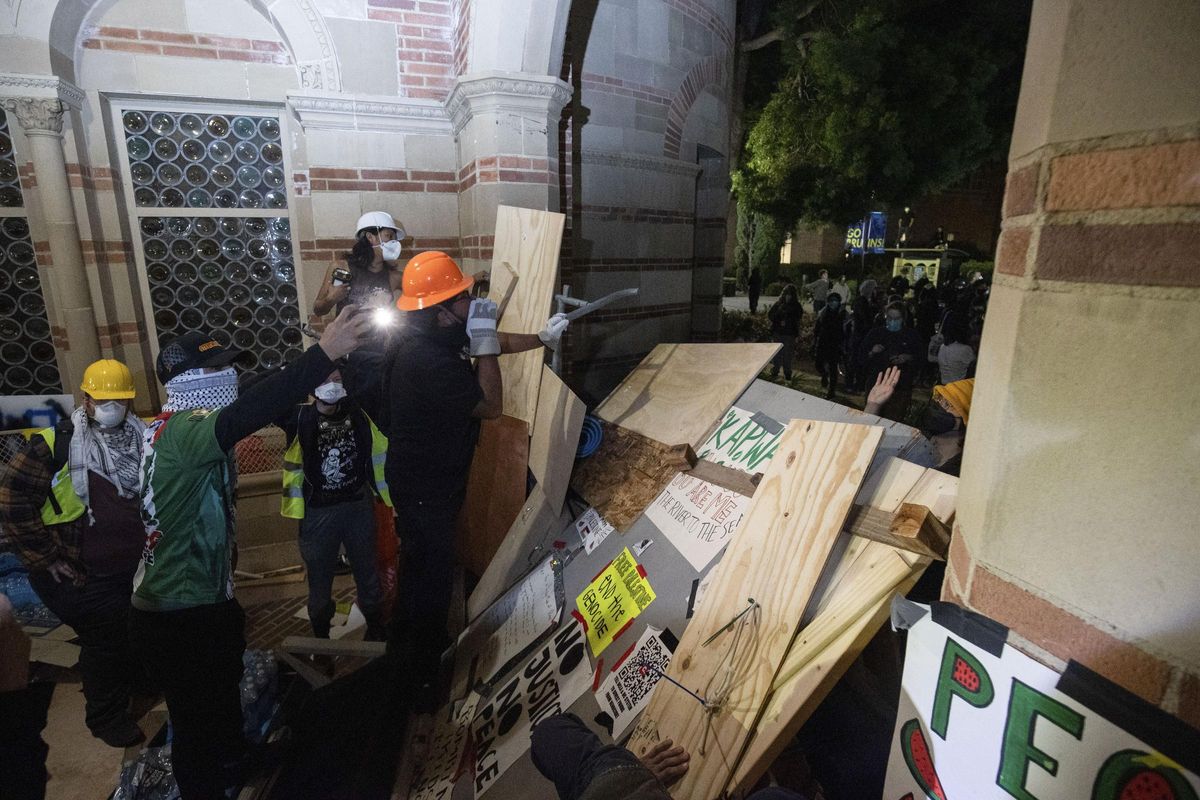 Pro-Palestinian demonstrators watch police activity behind a barricade on the UCLA campus Wednesday, May 1, 2024, in Los Angeles. (AP Photo/Ethan Swope)