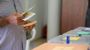 Un hombre sostiene sus papeletas de votación ante las urnas de la mesa en el colegio electoral este domingo 28 de mayo.