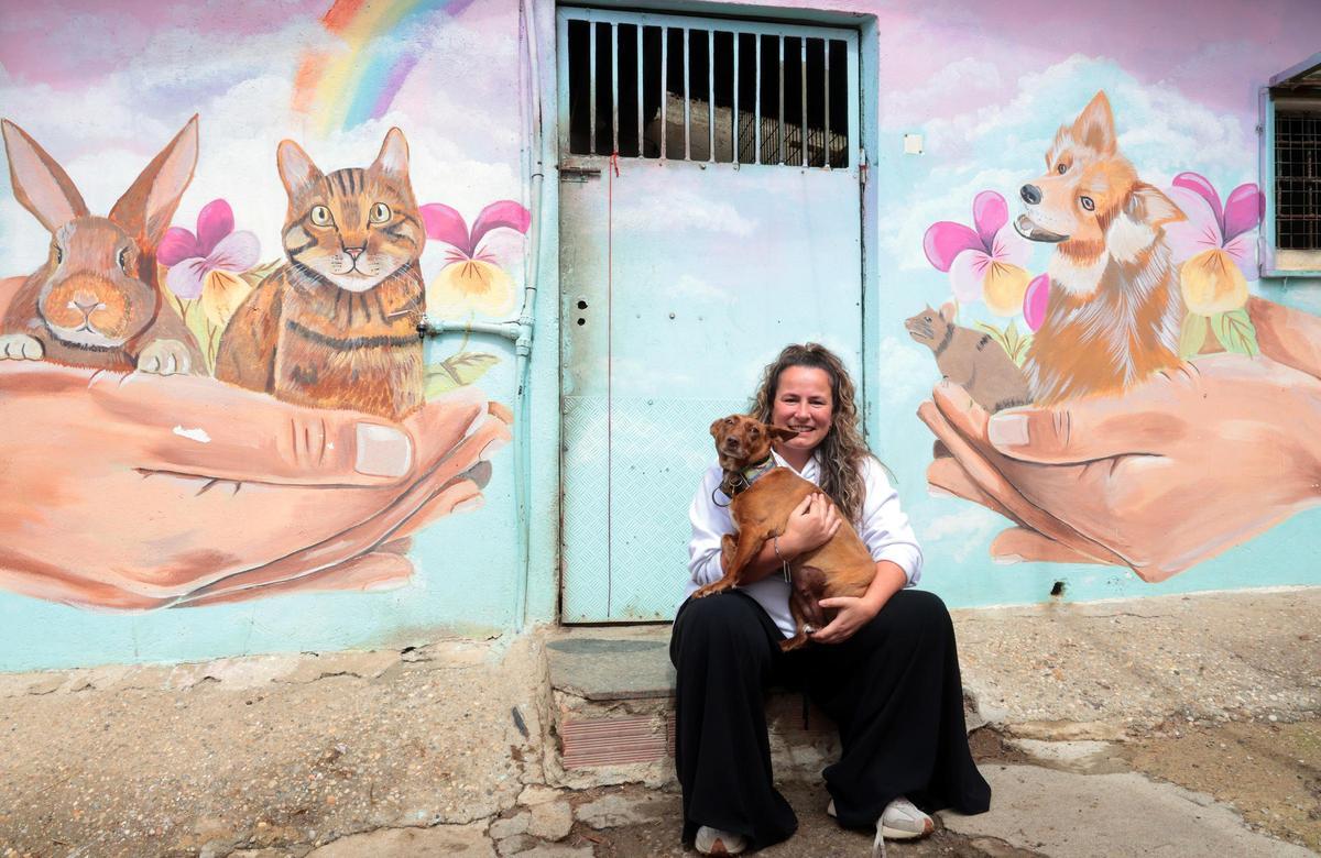 Eva Casais con la perrita Vivian ante otro de los murales que pintó en la protectora Os Biosbardos de Ponteareas