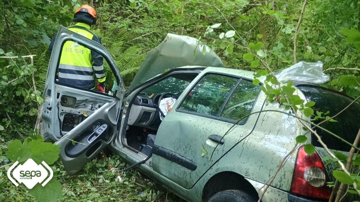 Un miembro de los servicios de rescate junto al vehículo siniestrado.