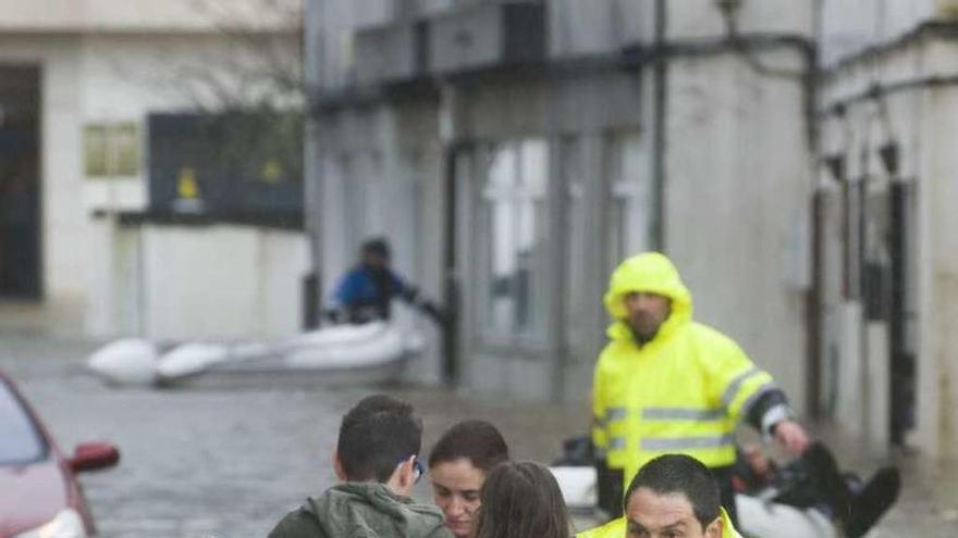 Un efectivo rescata a unos vecinos durante la inundación.