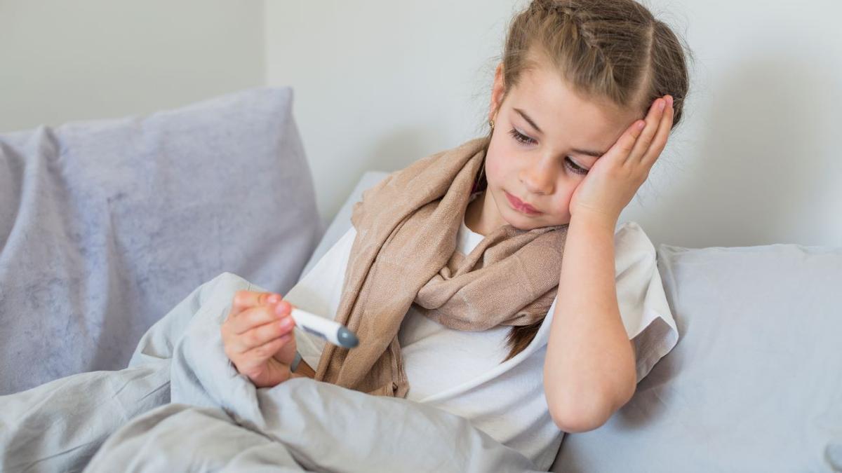 Una niña enferma usando el termómetro