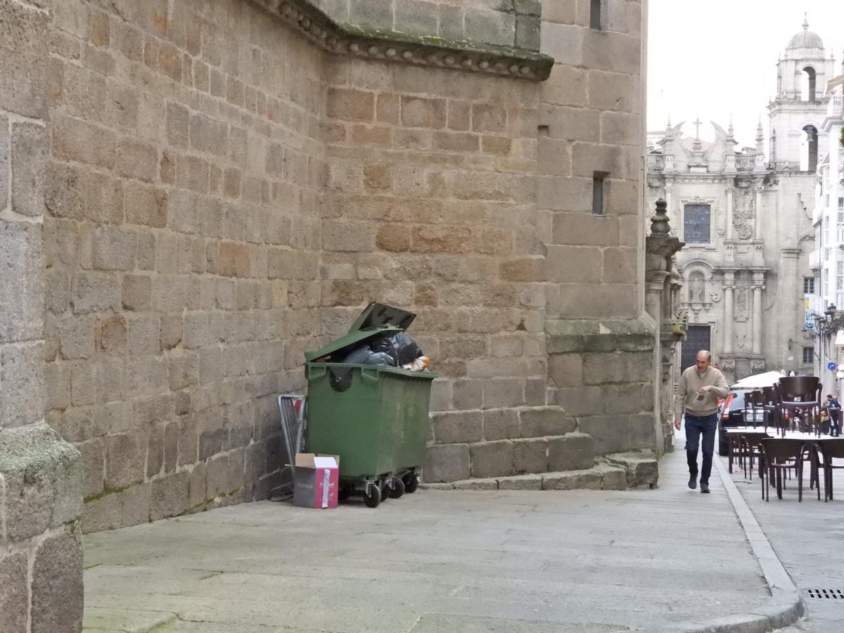 Un contenedor lleno de basura arrimado contra la catedral de Ourense, de los siglos XII y XIII. // FERNANDO CASANOVA