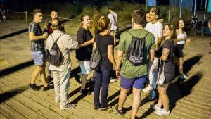 Varios mediadores, con mochilas negras, hablan con jóvenes de botellón en Castelldefels.