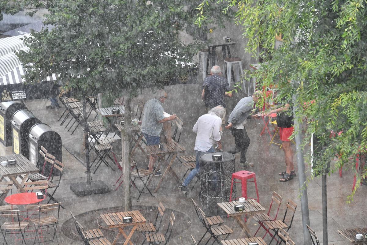 Personas sorprendidas por un chaparrón en una terraza