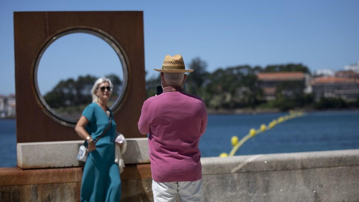 Un hombre saca una foto a una mujer en el paseo marítimo de Sanxenxo