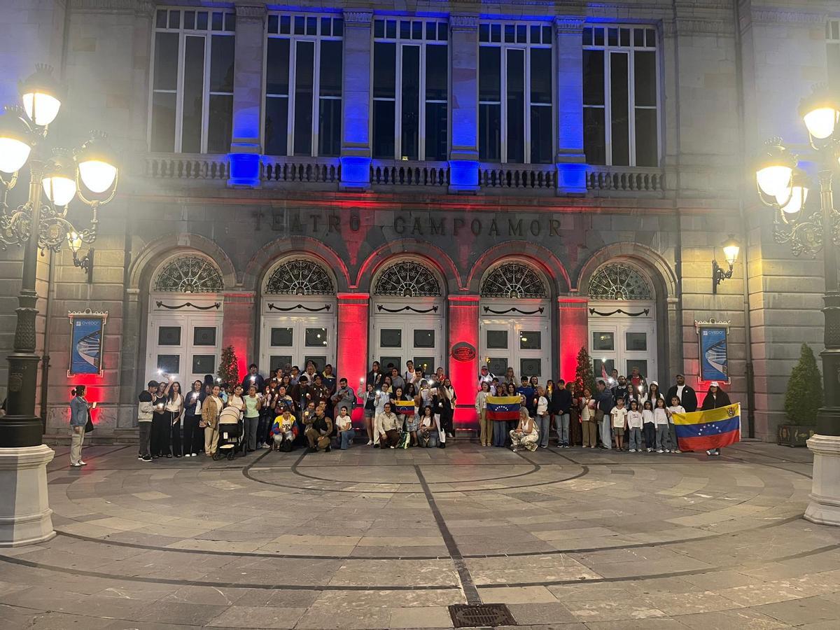 Un grupo de venezolanos, ante el teatro Campoamor, iluminado con los colores de la bandera de su país.
