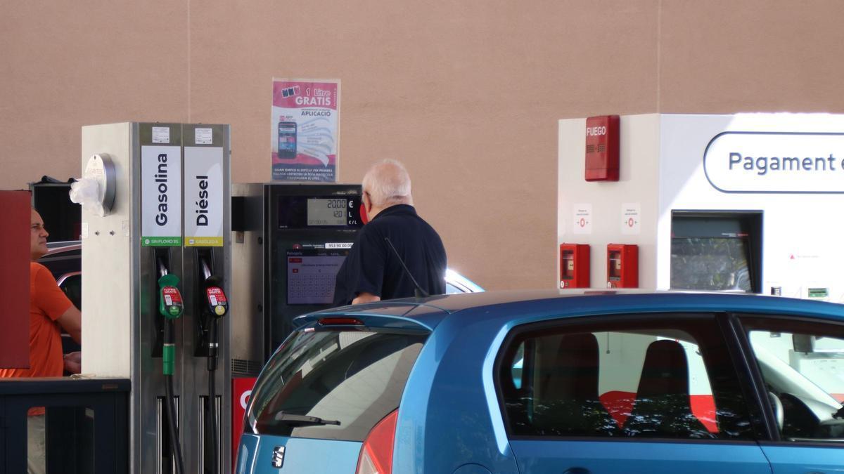 Una persona posant benzina al seu vehicle en una estació de baix cost