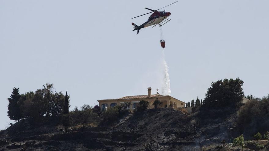 Un helicóptero trabaja, este domingo, en las tareas de extinción del incendio de Torrox, el último de gran calado declarado.
