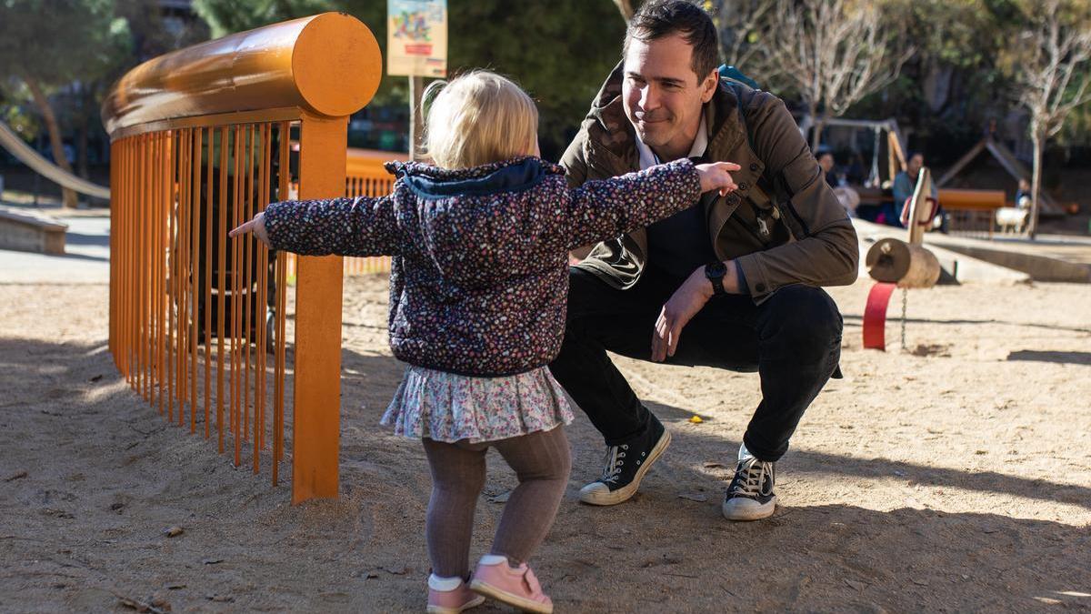 Un hombre juega con su hija en un parque de Barcelona.