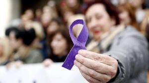 Una mujer sostiene un lazo violeta.