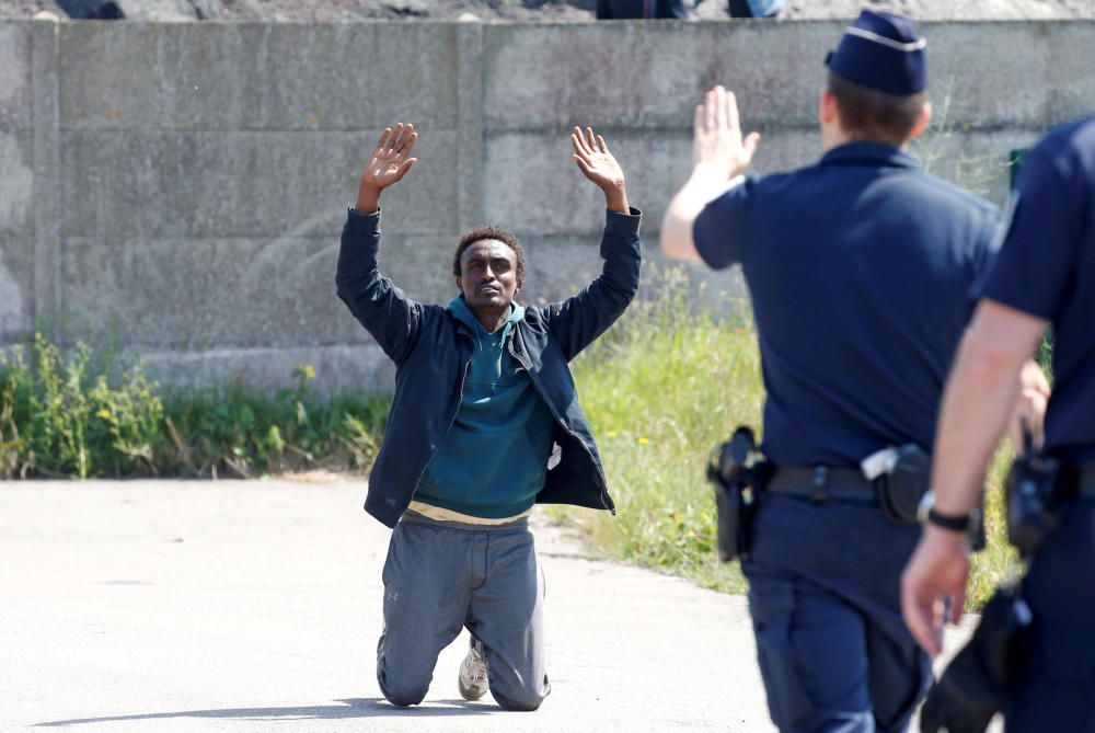 La policía antidisturbios francesa señala a un emigrante que está de rodillas mientras las autoridades francesas bloquean su acceso a un punto de distribución de alimentos en Calais, Francia. REUTERS.