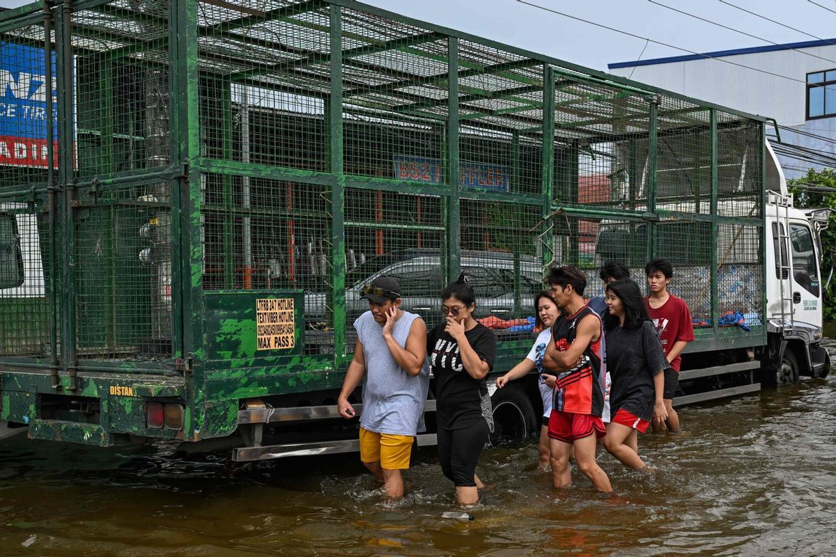 La gente camina a través de una calle inundada después de las fuertes lluvias traídas por el monzón del suroeste en Pampanga el 31 de agosto de 2026. (Foto de Jam STA ROSA / AFP)