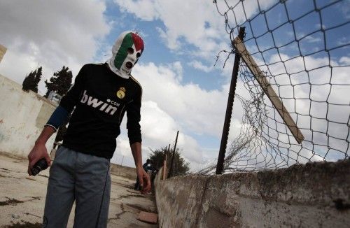 Un manifestante palestino sostiene una granada de gas lacrimógeno durante los enfrentamientos con las fuerzas de seguridad israelíes