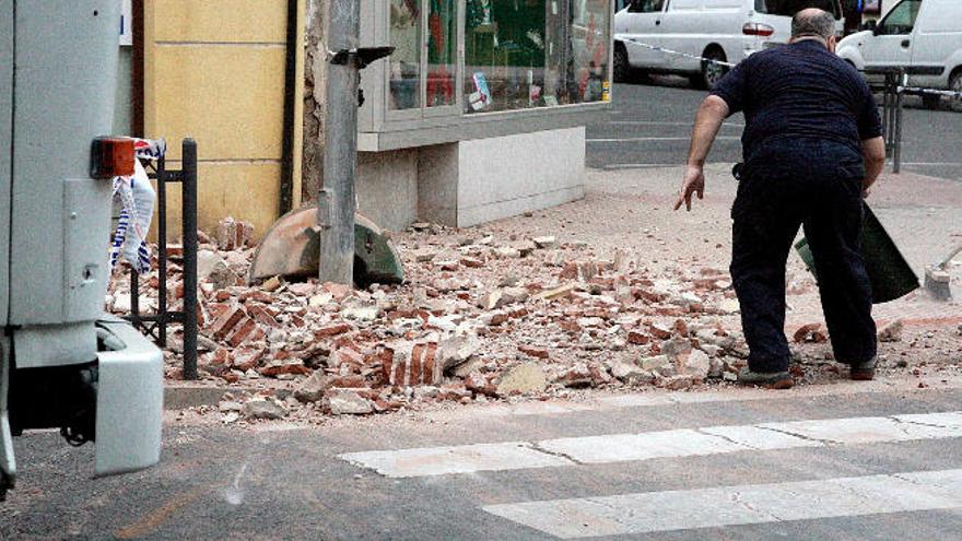 Un vecino junto a numerosos cascotes caídos desde un edificio en una de las calles de la ciudad autónoma.