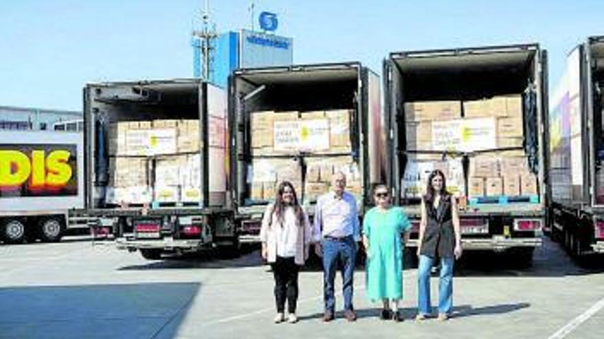 Directivos de la empresa, ante tres camiones con donaciones.